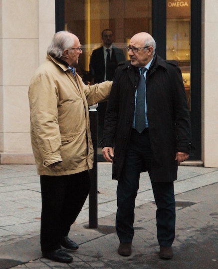Two older men standing and talking about business